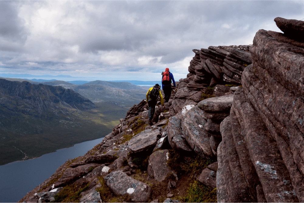 Two hikers scrambling through the mountains