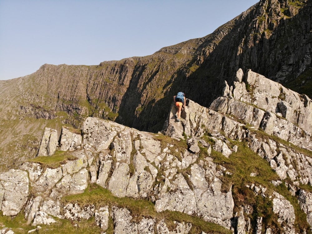 Female hiker scrambling over rocks