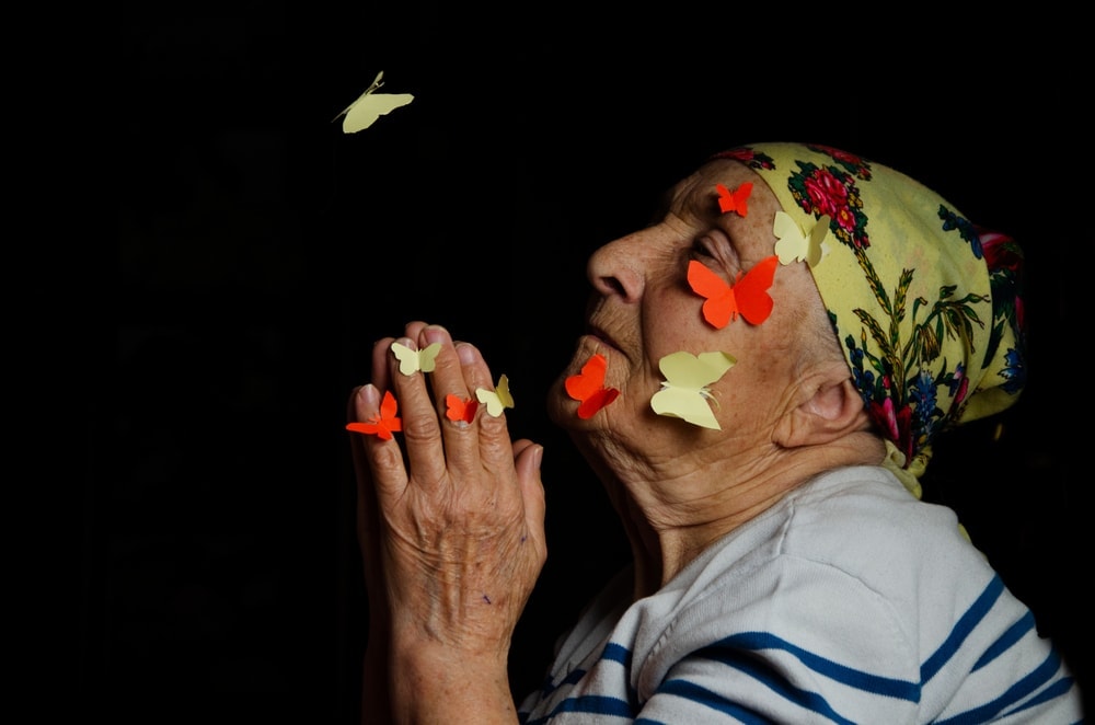 a grandmother with butterflies on her face praying