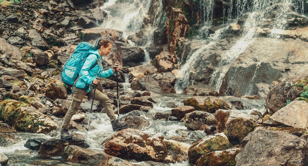 Woman using trekking poles on rocks