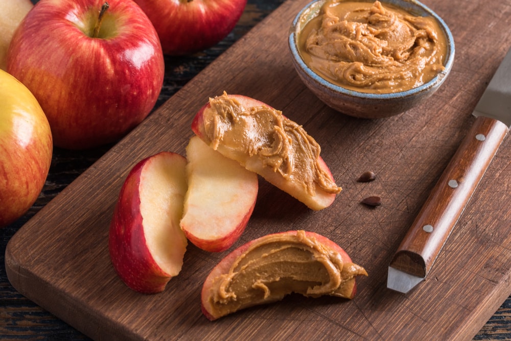 Apple and peanut butter on a chopping board