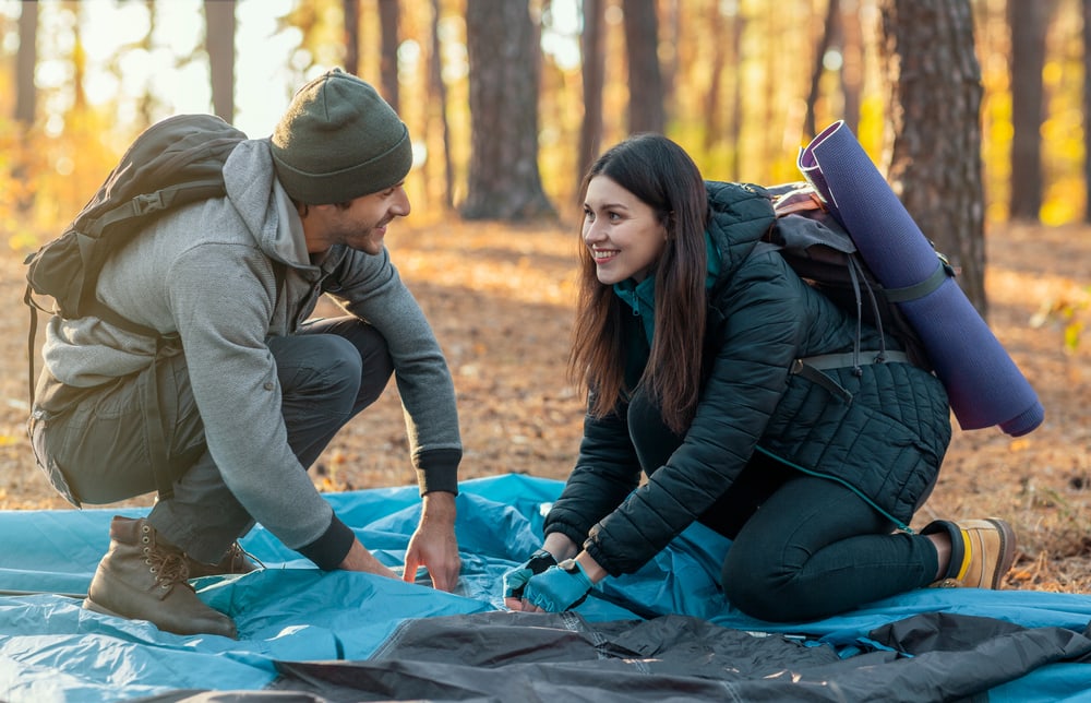 Couple happily building their tent in forest