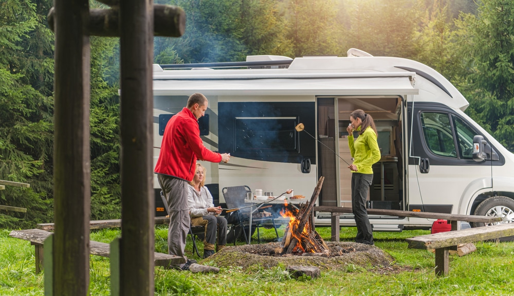 friends enjoying a camp with their modern RV camper. RV camping is one of the beautiful camping styles to get into the woods while enjoying modern-day amenities