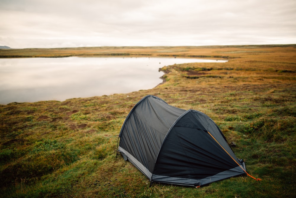 a lone tent on a campsite near a lake