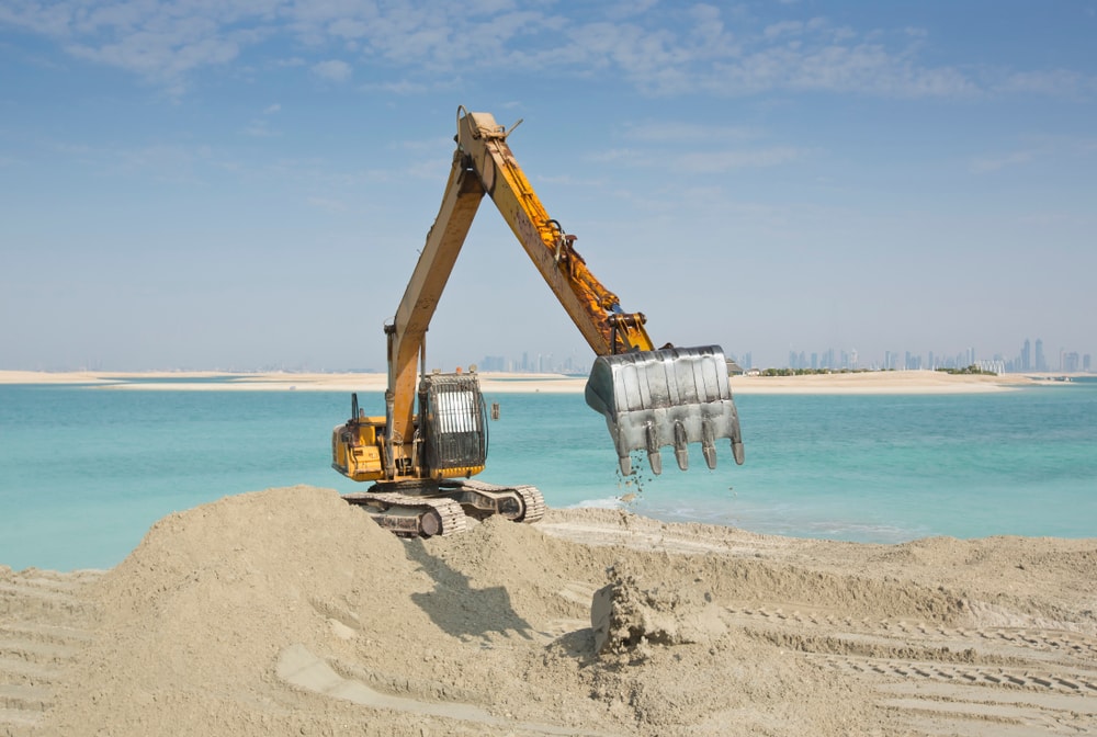Large scale marine land reclamation and artificial island building showing dredged coral sand and erosion of shoreline