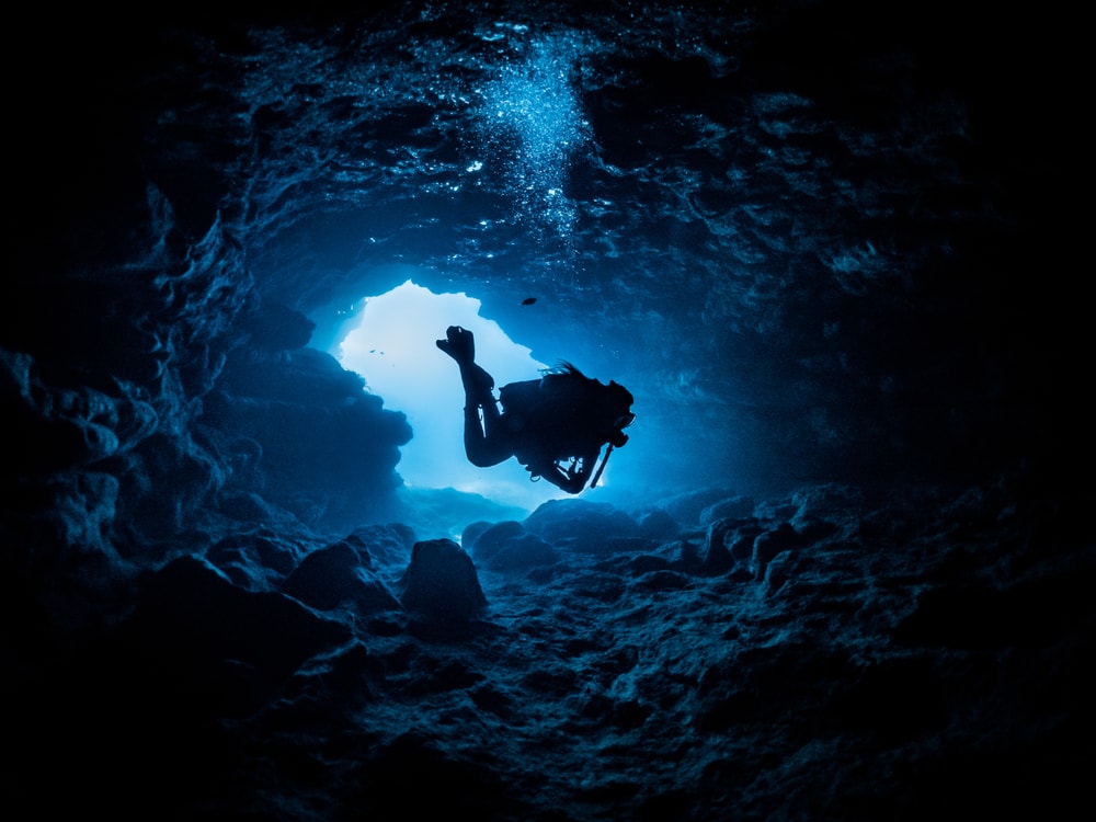 Diver going inside the cave of the deep ocean