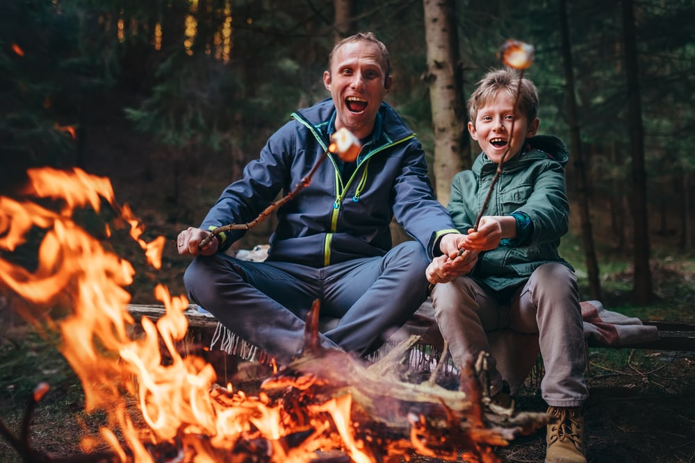 Father and son happily cooking their marshmallow on fire