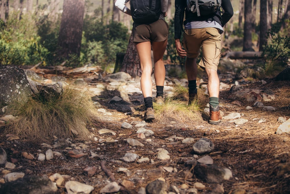 Hiker couple exploring nature walking through the woods.