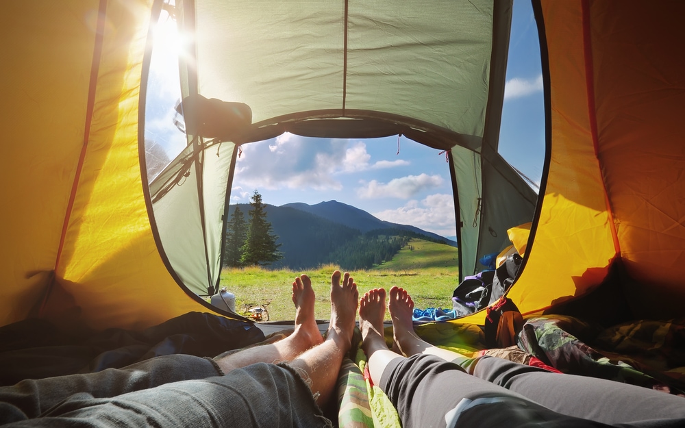Two people lying in tent with a view of mountains