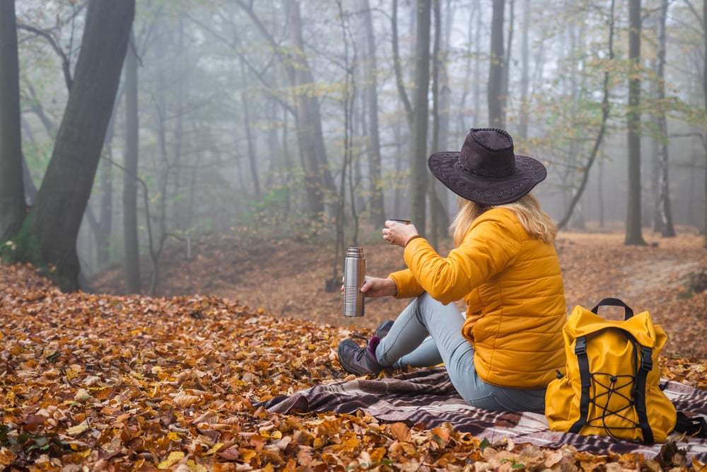 a woman sitting on a sheet in the forest 