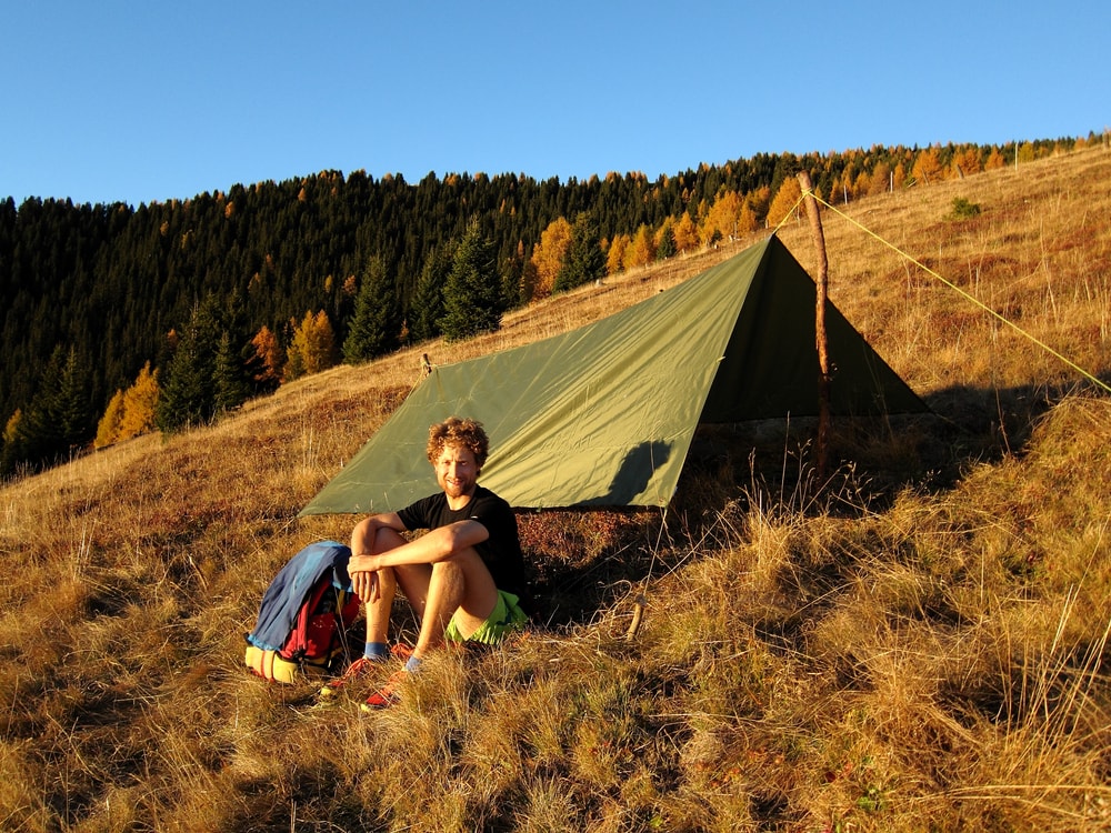 A man sitting in front of a tarp tent